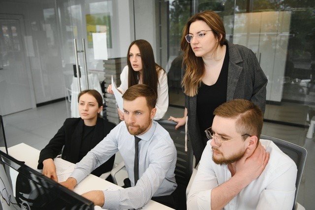Smiling Business People Sitting At A Desk In Front Of A Laptop Computer