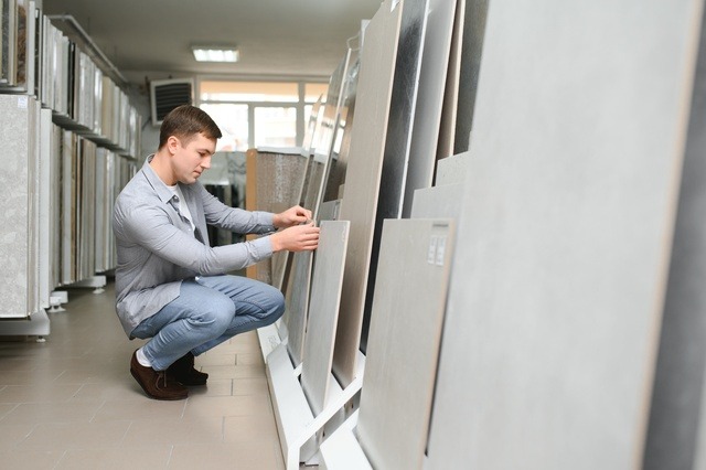 Young Man Choosing Tiles At Building Market